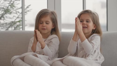Two Blonde Girls Smiling and Playing on Couch