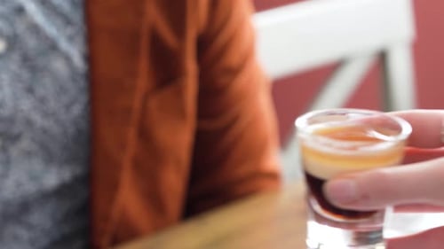 Hands Of A Carefree Romantic Couple At The Bar Cheering Glasses Of B-52 Cocktail Drinks. closeup