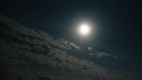 Dramatic Clouds Move Past Shining Full Moon at Night