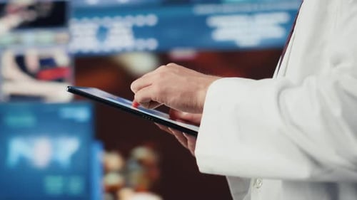 Doctor using tablet in front of medical monitors