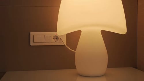 Hand der Frau drückt den Knopf am weißen Schalter, um die Lampe auszuschalten