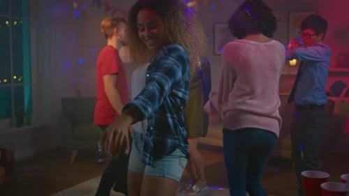 At the Wild House Party: Beautiful Black Girl Seductively Dances in Neon Lights. In the Background