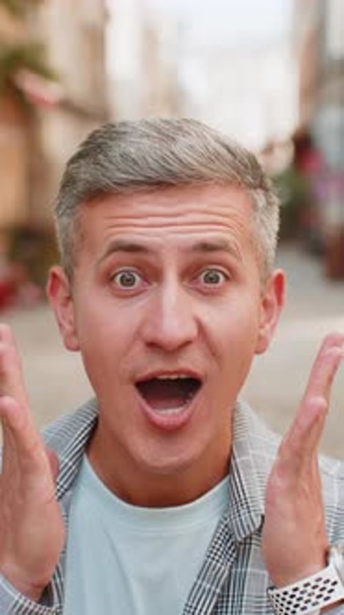 Mature Man Looking Surprised at Camera with Big Open Eyes Shocked By Sudden Victory on Street