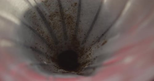 Plan rapproché, au ralenti, du marc de café déposé dans un filtre à café V60 afin de préparer un