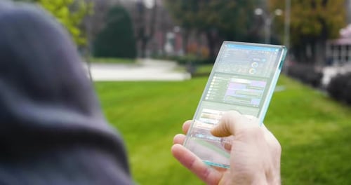 Die Hand eines Mannes in Anzügen verwendet ein futuristisches Glastelefon mit der neuesten holografischen Technologie