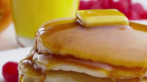 Köstlicher goldener Pfannkuchen im Stapel mit Sirup, Butter und Orangensaft