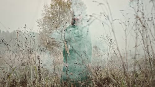 Model posing with green smoke in a field