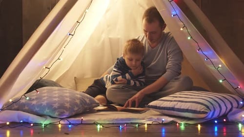 Father Reading Book to Child in Tent