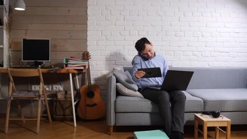 Man Works on Laptop and Tablet at Home