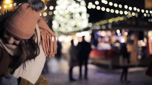 Happy young couple embracing at christmas market during winter holidays evening
