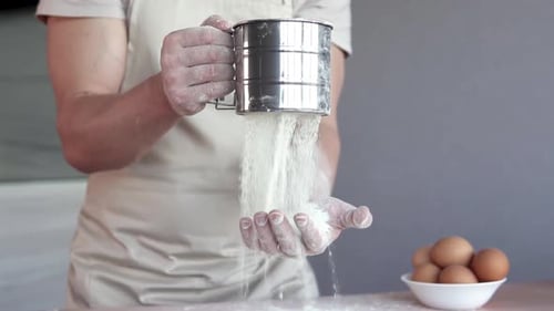 Adult sieving flour on his hand
