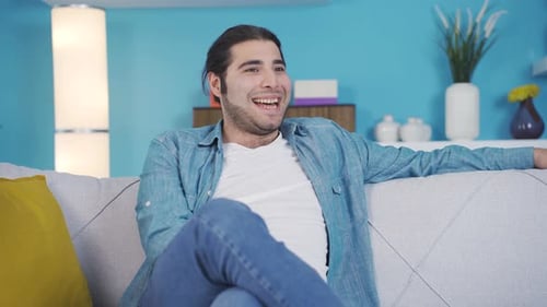 Cheerful and playful young man is sitting on the sofa.