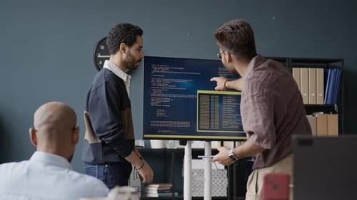 Une équipe informatique multiethnique motivée analyse le Code à l'écran lors d'une réunion de bureau