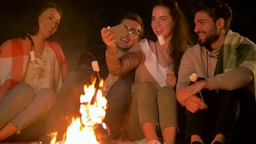 Leisure and People Concept - Group of Smiling Friends Sitting at Camp