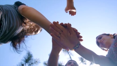 Friends Joining Hands Together Under Blue Sky