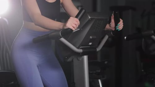 A Young Athletic Girl is Engaged in an Exercise Bike