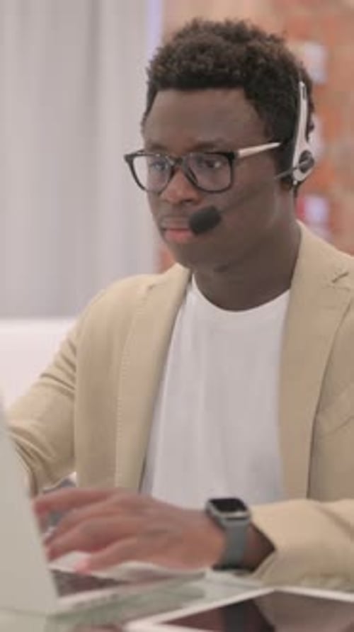 Young Adult Man Working at Computer with Headset