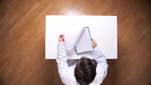 Doctor Wearing a Lab Coat and Writing with a Pencil on a Clipboard Flipping Through Patient Medical