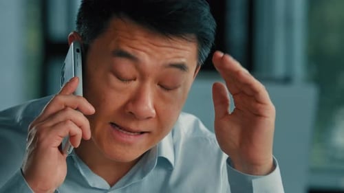 Serious Man Talking on Mobile Phone Indoors