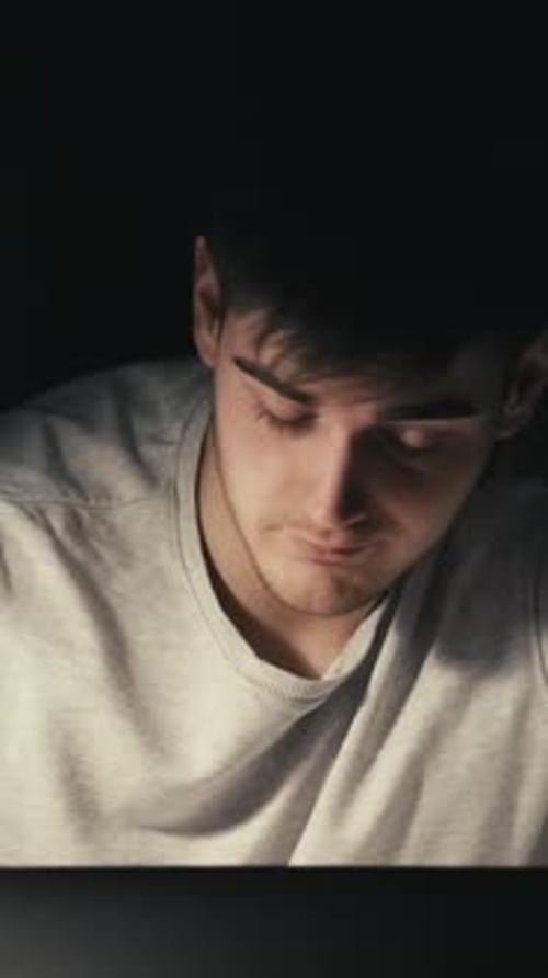 Tired Young Adult Working on Laptop at Night