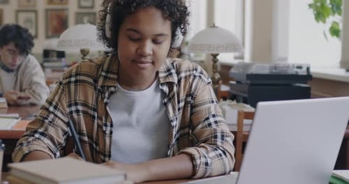 College Student Studying in Library with Laptop