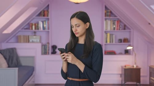Young Woman Uses Smartphone in Cozy Attic Space