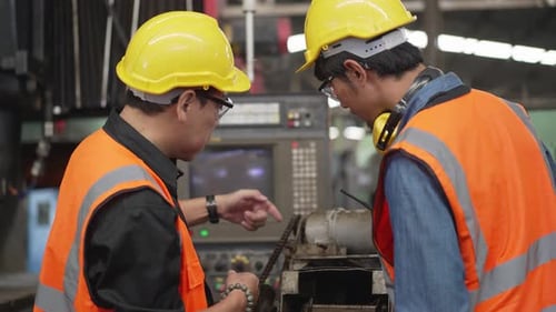 Asian male factory worker operating control big machine with colleagues assistant