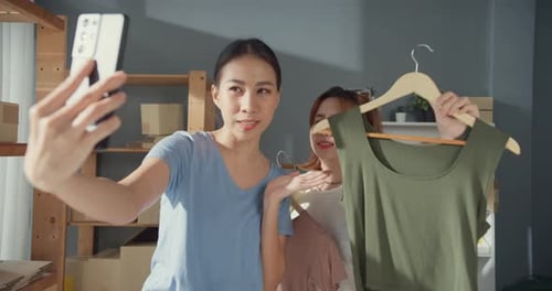 young Asian successful lady owner teenage partner with casual hold smartphone live stream.