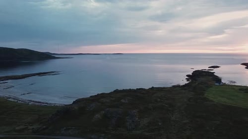 Sunset over the bay with a beach, without people. Aerial, backward camera move.