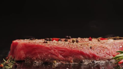 Fresh Marbled Beef with Pepper Salt and Rosemary Closeup Macro Cooking Juicy Steak on Grill with Oil