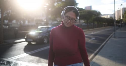 Woman Walking on City Sidewalk with Headphones On