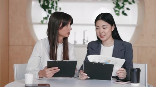 Two Young Women Collaborating in Modern Workplace Setting