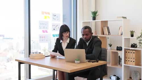 Colleagues Work Together at Desk in Office