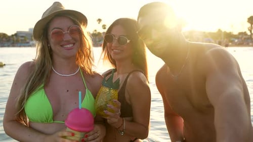 Smiling Friends Enjoying Beach Drinks at Sunset