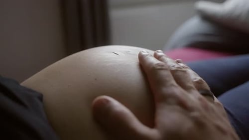 Fathers hand stroking baby mamas pregnant belly