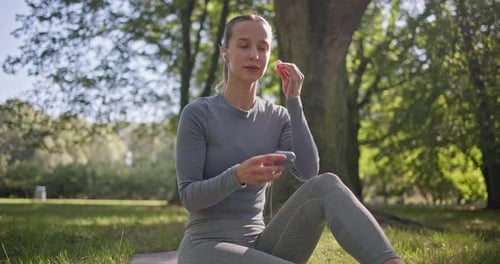 A Young Beautiful White Girl Practices Yoga in the Park and Meditates in the Lotus Position Among