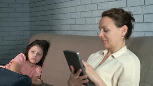 Child and Adult with Tablet on Sofa