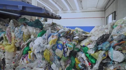 A garbage truck unloading plastic waste inside a recycling center