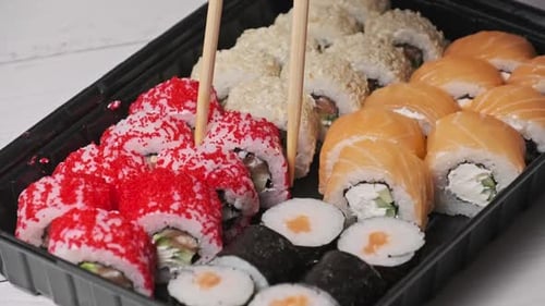 Sticks Take Sushi From the Plastic Sushi Box CloseUp