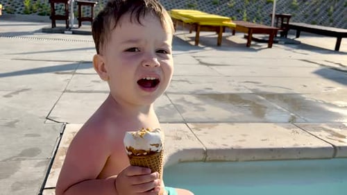adorable kids siblings brothers on pool edge eating cone ice cream,legs feet playing into water wave