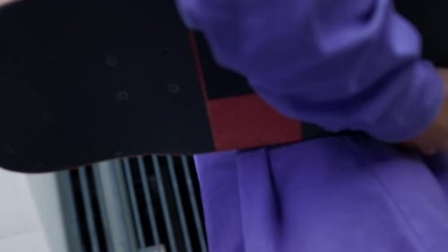 Sporty skater guy walking with skateboard on city street going to stadium workout