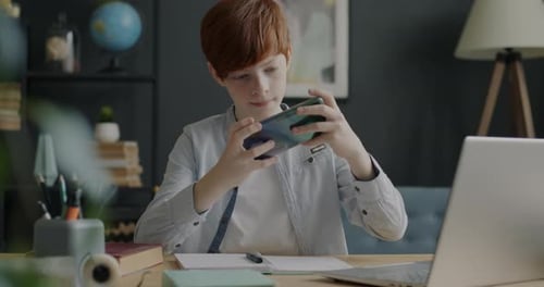 Child Plays Game on Smartphone at Desk