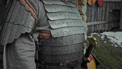 Guerrier masculin avec plastron et casque debout près d'une clôture en bois