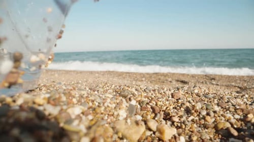 Crumpled bottle lying on the beach. The sea is in the background. Garbage on the shore. Planet pollu