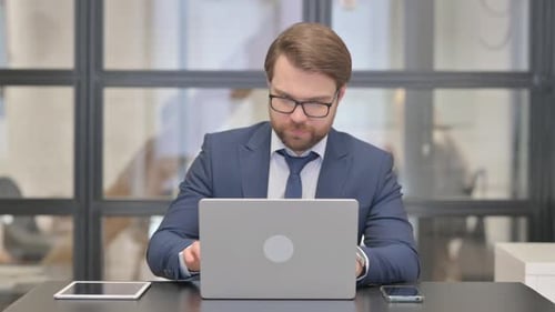 Man in Suit at Laptop in Office Meeting
