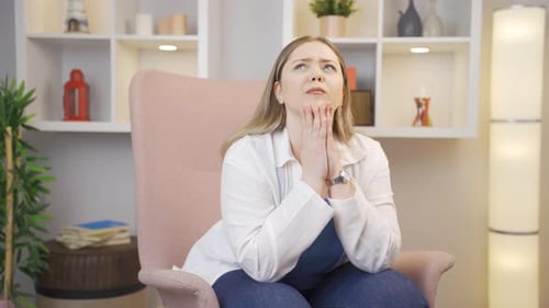 Worried Woman Sitting in Armchair in Living Room