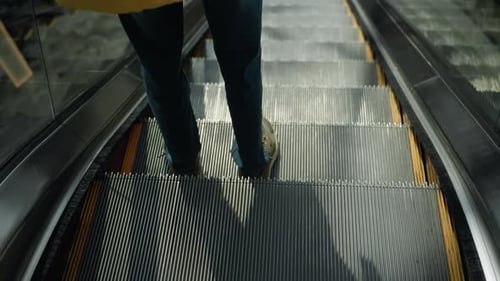 Personne portant un jean bleu descendant un escalator