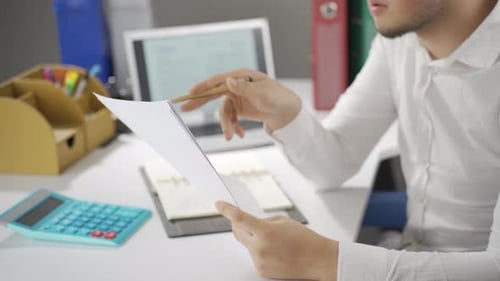 Man Reviews Paperwork in Bright Office Setting