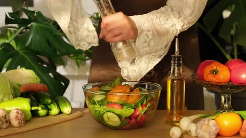 Making vegetable salad in the kitchen. Woman cooking salad from fresh vegetables