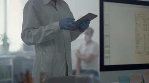 Unknown medicine worker typing patient information on tablet in modern office